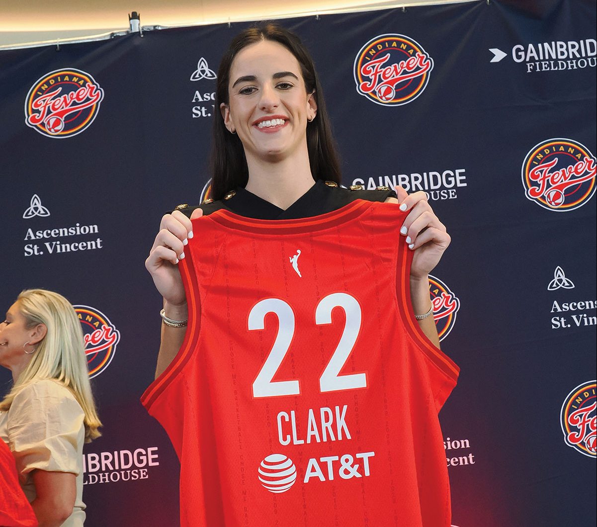 Caitlin Clark smiles as she presents her jersey.